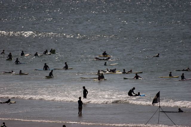 People in the water and surfing on Polzeath Beach, in Polzeath, Cornwall.