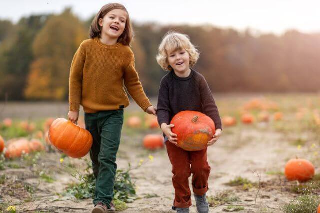 Two kids picking pumpkins.