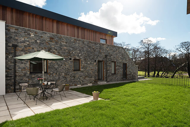 Enclosed garden with patio and grass.