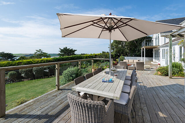 Daymer Dunes holiday cottage - view of exterior decked terrace with umbrella and coastal views.