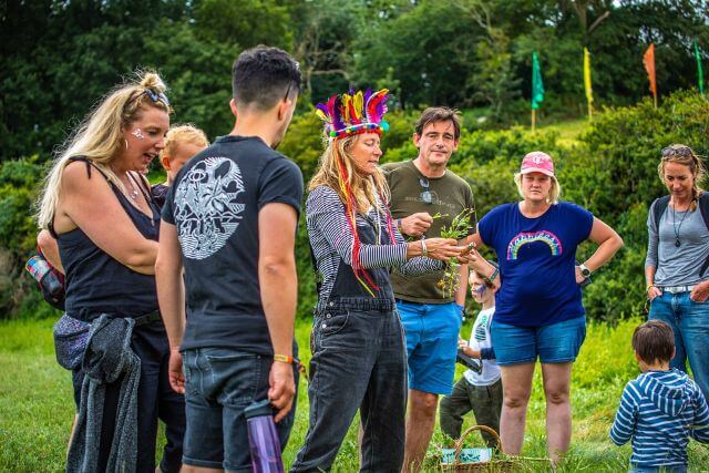 A woman teaches a foraging class to a group in a field.