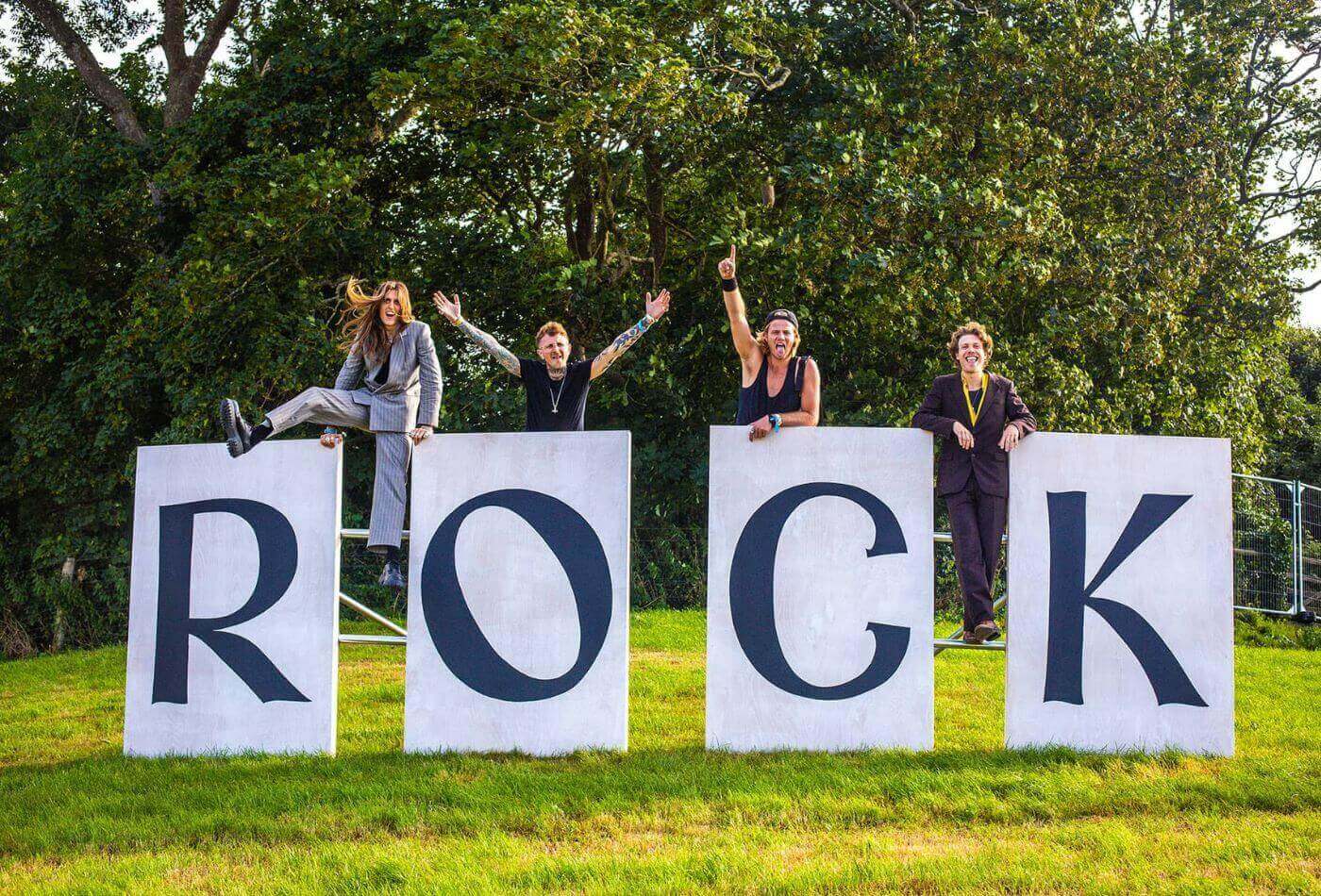 Four people stood on large 'ROCK' sign at Rock Oyster festival in north Cornwall.