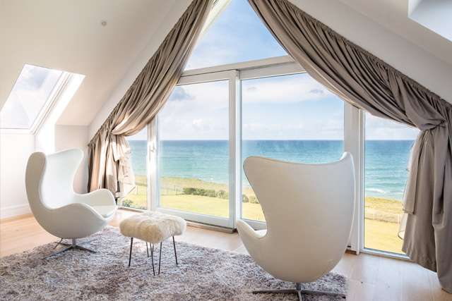 Sea view through a large, room-high window, on a sunny day at Seascape, Polzeath